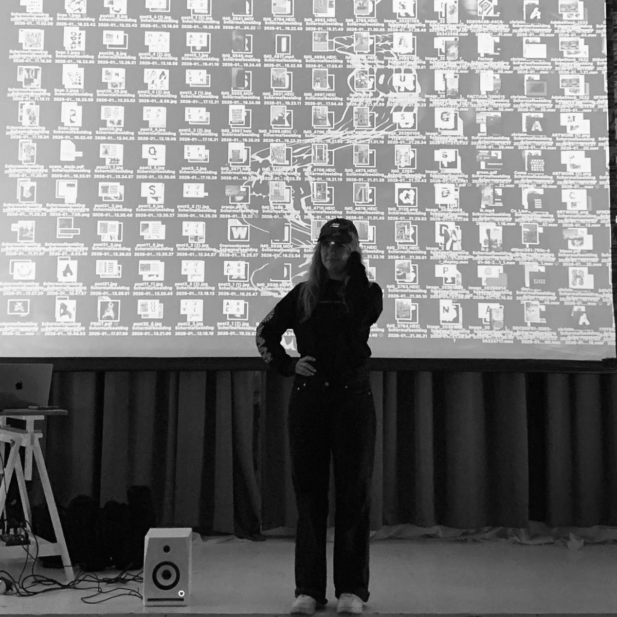 Laura Ketting on stage during a talk, in front of a projection of her work files